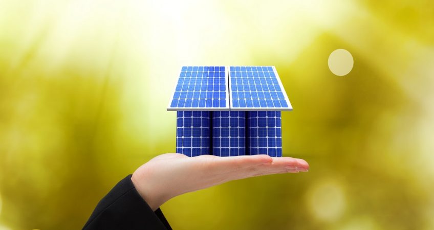 the-photo-with-solar-panels-and-a-womans-palm-holding-a-toy-house